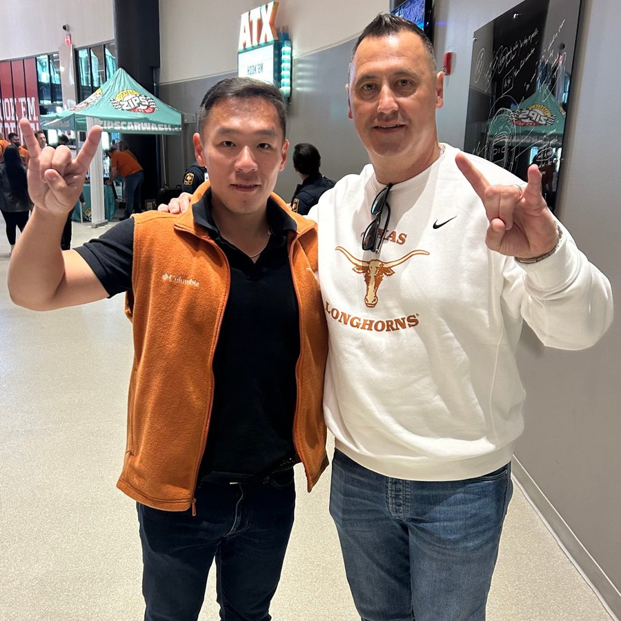 Kai Huang making the Hook 'em sign at a Texas Longhorns game